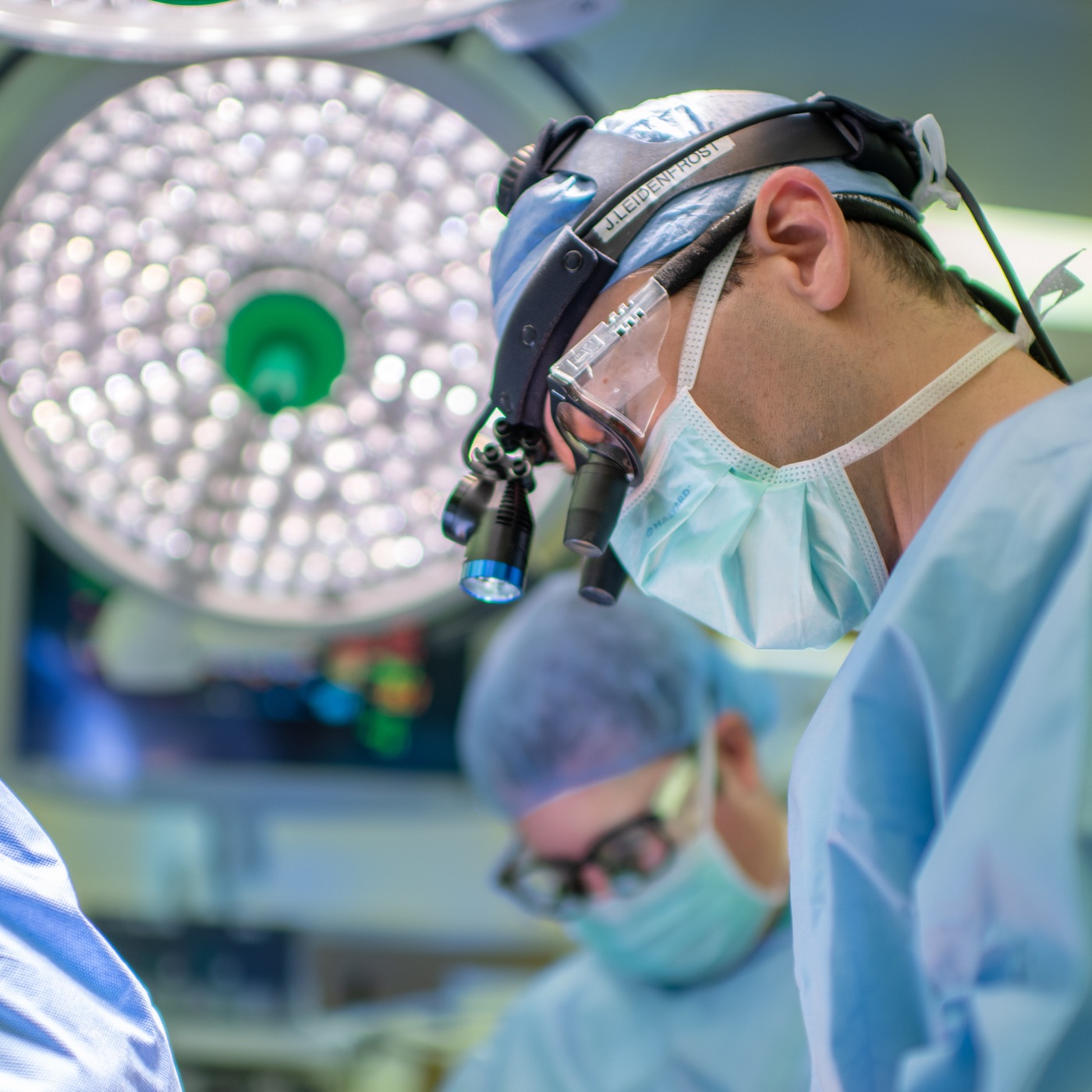 The founder in the operating room, wearing surgical loupes and a headlight